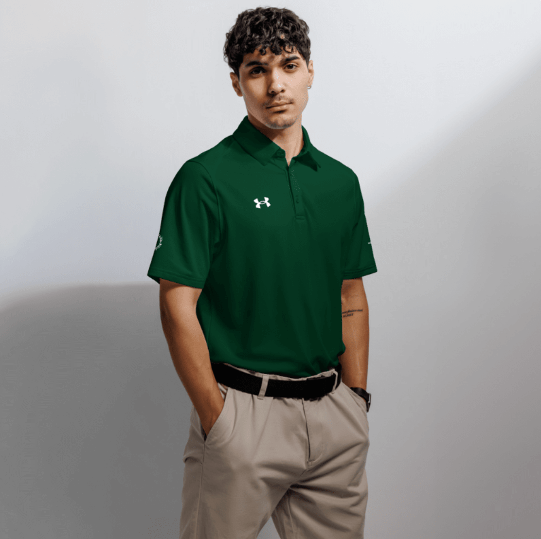 Man wearing Under Armour x SCHWITT SHOT green polo, studio shot on a white background