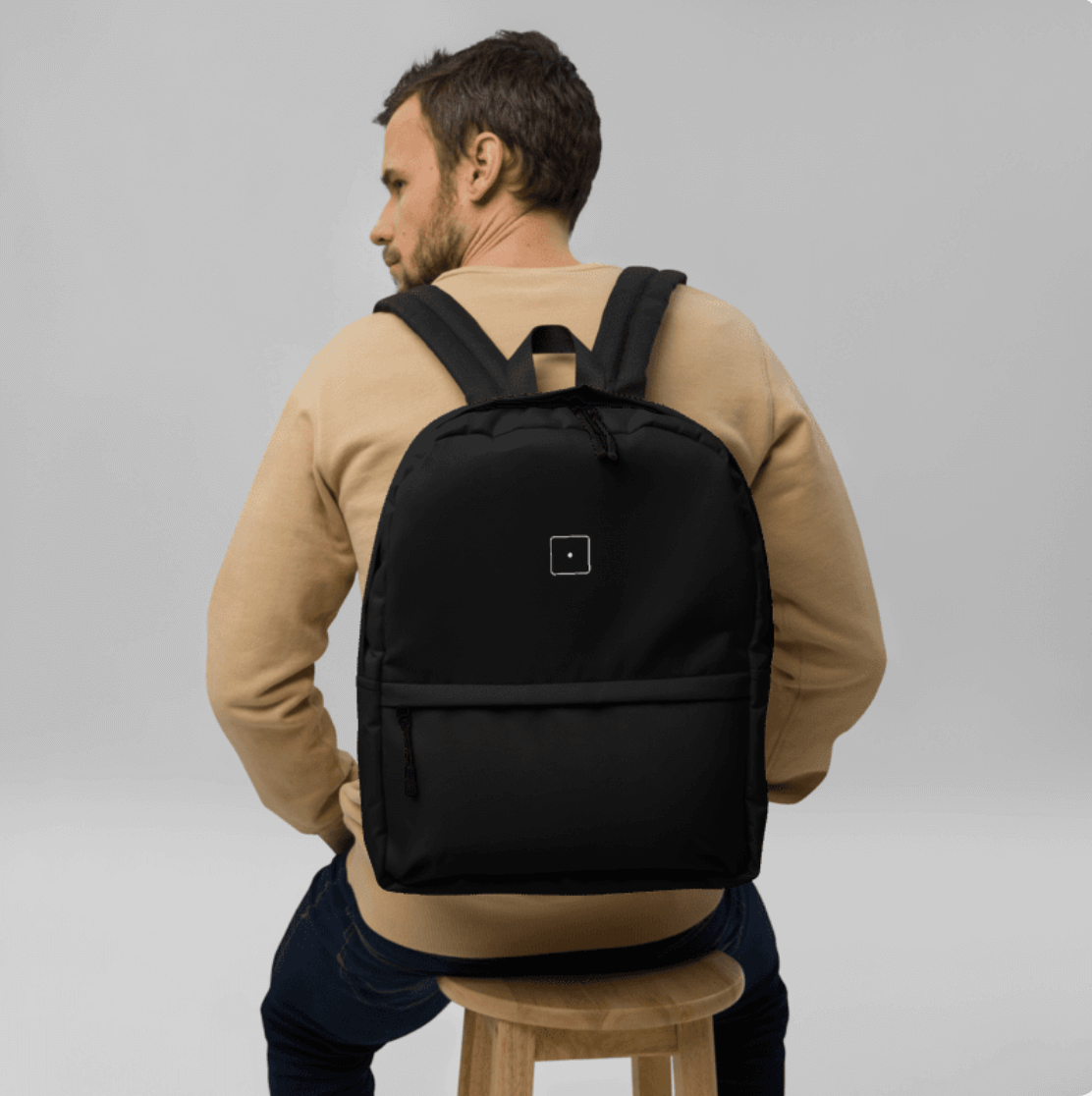 SCHWITT SHOT Black Label Ultra Premium Backpack Black worn by a man sitting on a chair, front view