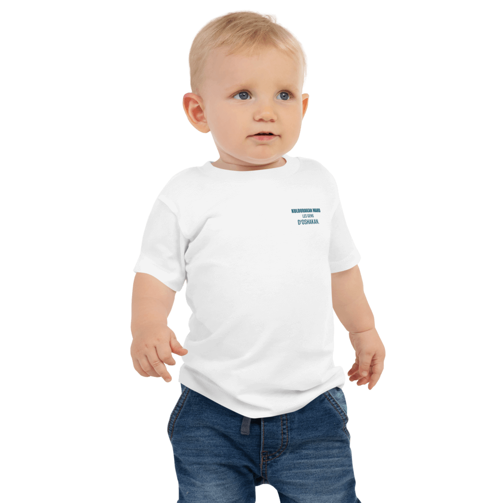 Toddler wearing white 'KULDURAKAN MARD' t-shirt with green text, showcasing cultural roots and style.